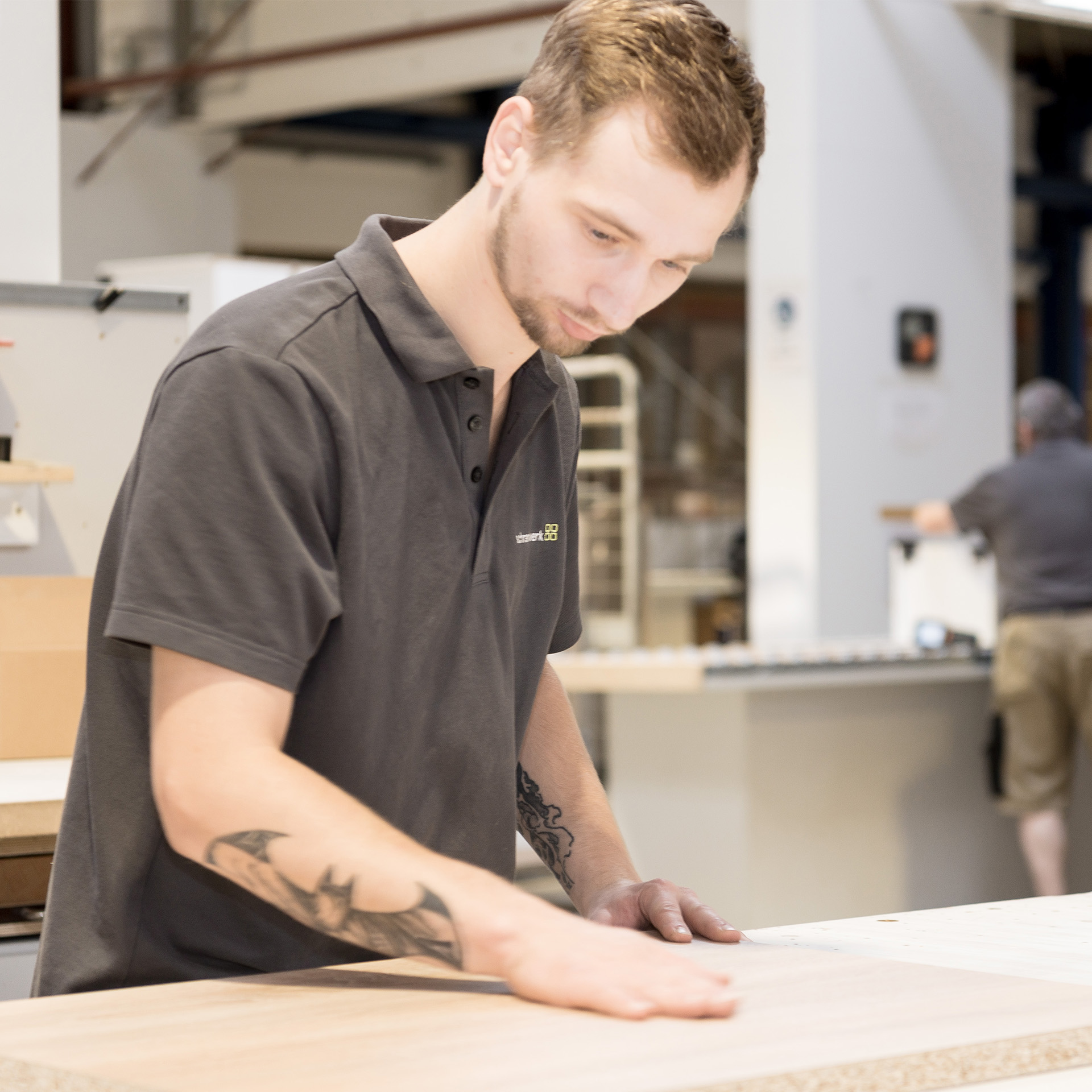 Unsere_Qualitaet - Mann steht am Schreinertisch und kontrolliert die Qualität